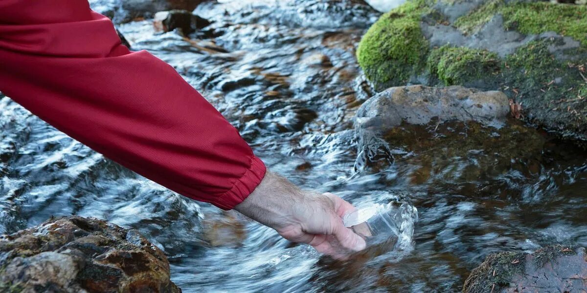 Плавно текущий. С человека течет вода. Water sampling. Проба воды на горе. Выплеска более.