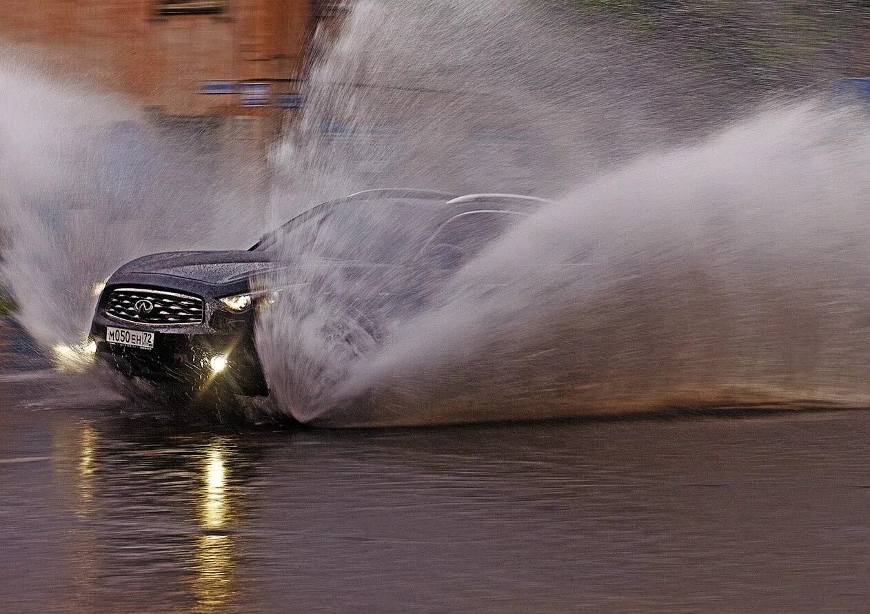 После дождя завелся. Брызги от машины. Машина в воде. Машина проезжает по луже. Машина в брызгах воды.