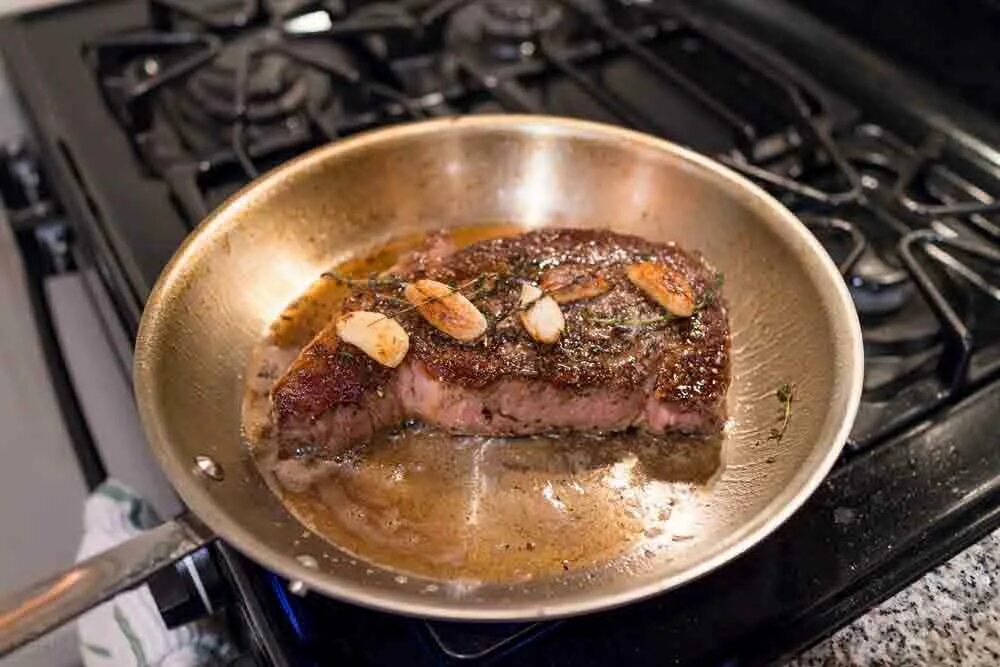 Есть сырое плохо проваренное прожаренное мясо. Мясо на сковороде. Стейк на сковороде. Жарка мяса. Стейк жариться на ск5оворподки.