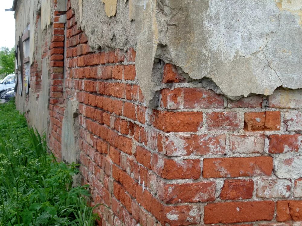 Разрушение стены здания. Разрушенное кирпичное здание. разрушение штукатурного слоя. разрушение штукатурного слоя фасада. трещина в кирпичной стене.