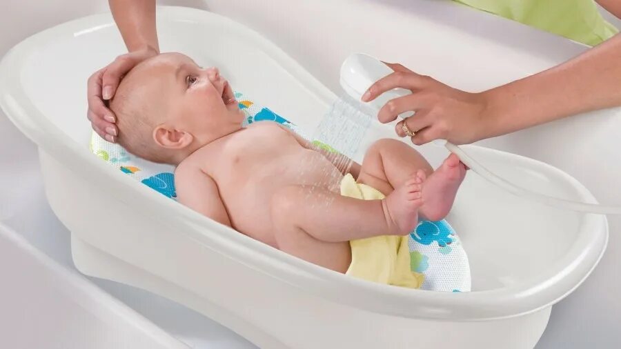 Мама измеряет температуру воды для купания ребенка. Купание малыша в ванночке. Ванночка для купания новорожденного. Купание новорожденного ребенка. Для купания новорожденных приспособления в ванную.
