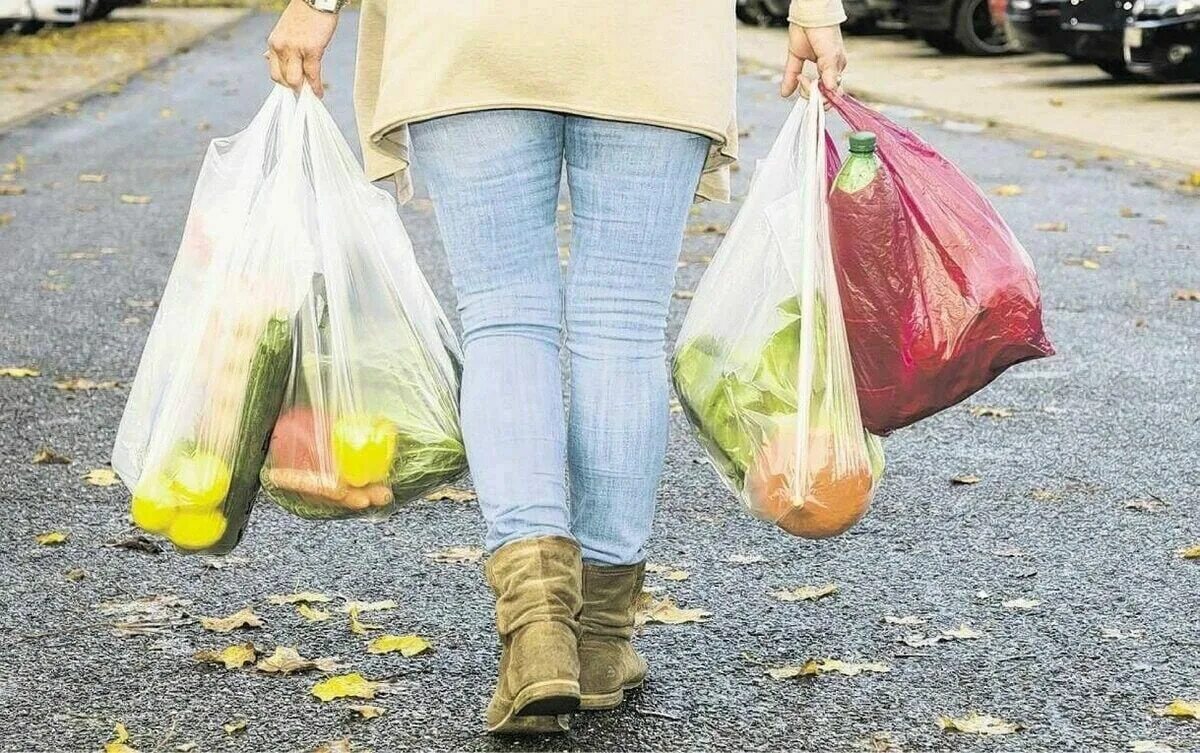 Выбирая покупку или расплачиваясь сумку. Тяжелые сумки с продуктами. Пластиковый пакет с продуктами. Тяжелая сумка. Женщина несет пакеты с продуктами.