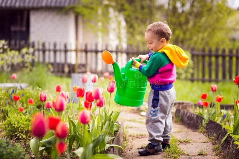 Дети поливают растения. Мальчик поливает цветы. Мальчик с лейкой. Дети помогают в саду сажать.