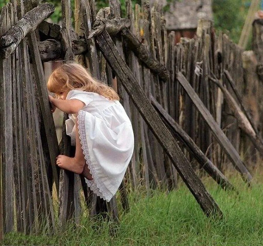 Деревенское подглядывание. Заглядывает за забор. Фотосессия у забора. Девочка на заборе.