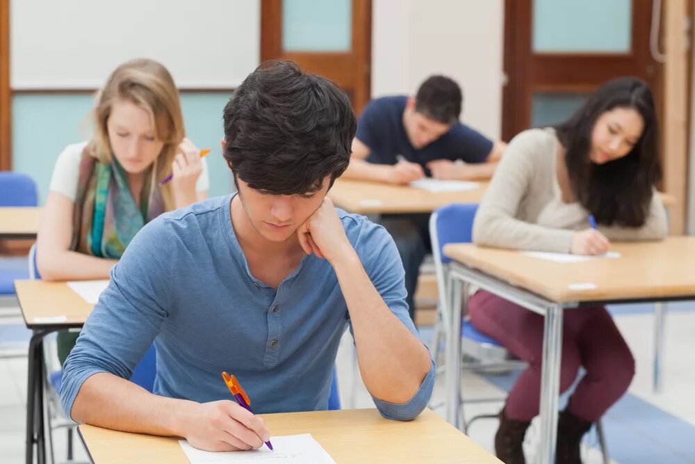 She study for her exams. Студент за партой. Человек за партой. Студентка сдает экзамен. Группа студентов.