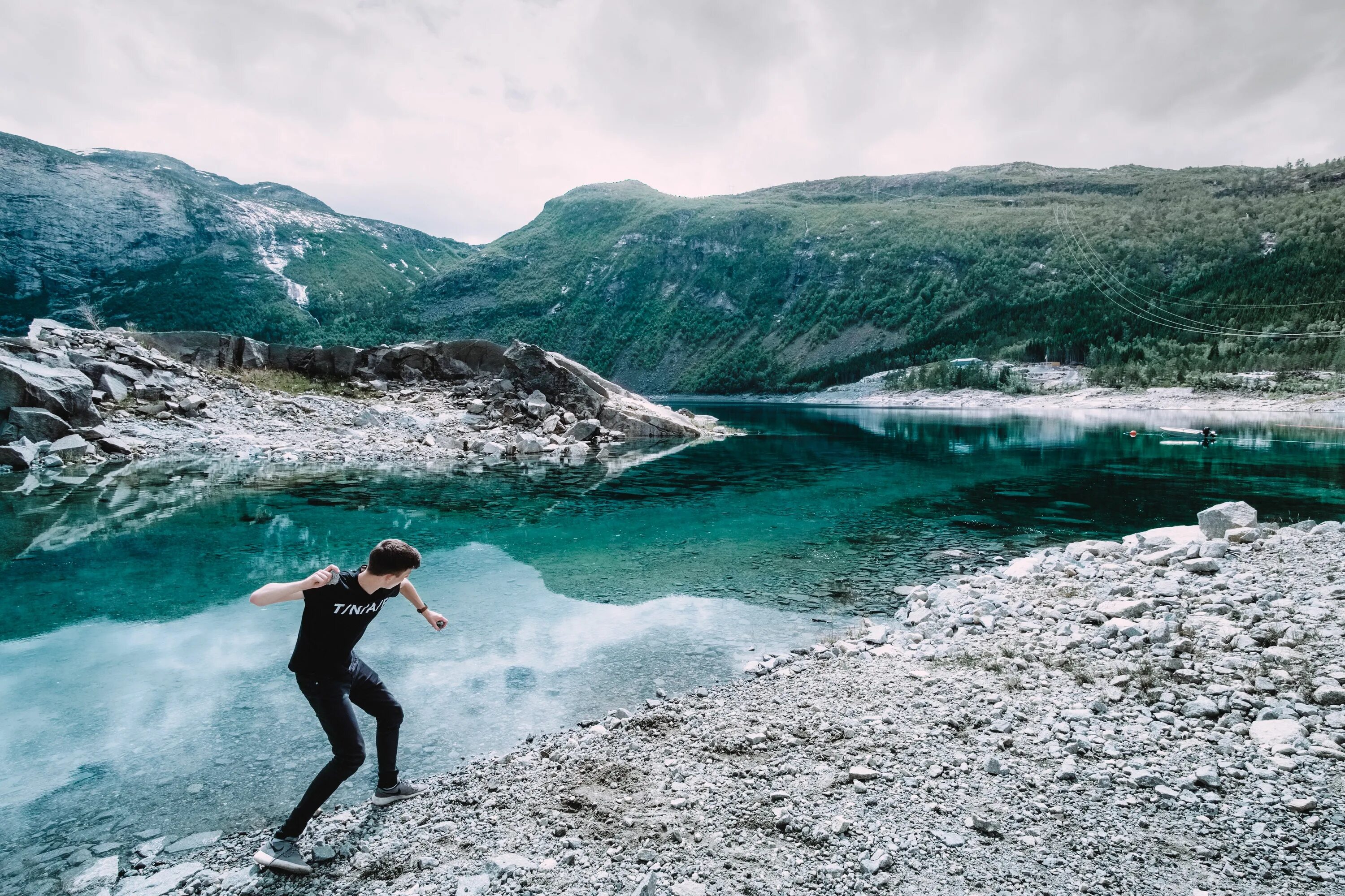 Skipping stones. Стоунскиппинг. Брошенный камень. Мальчик кидает камень в воду. Активности на природе фото.