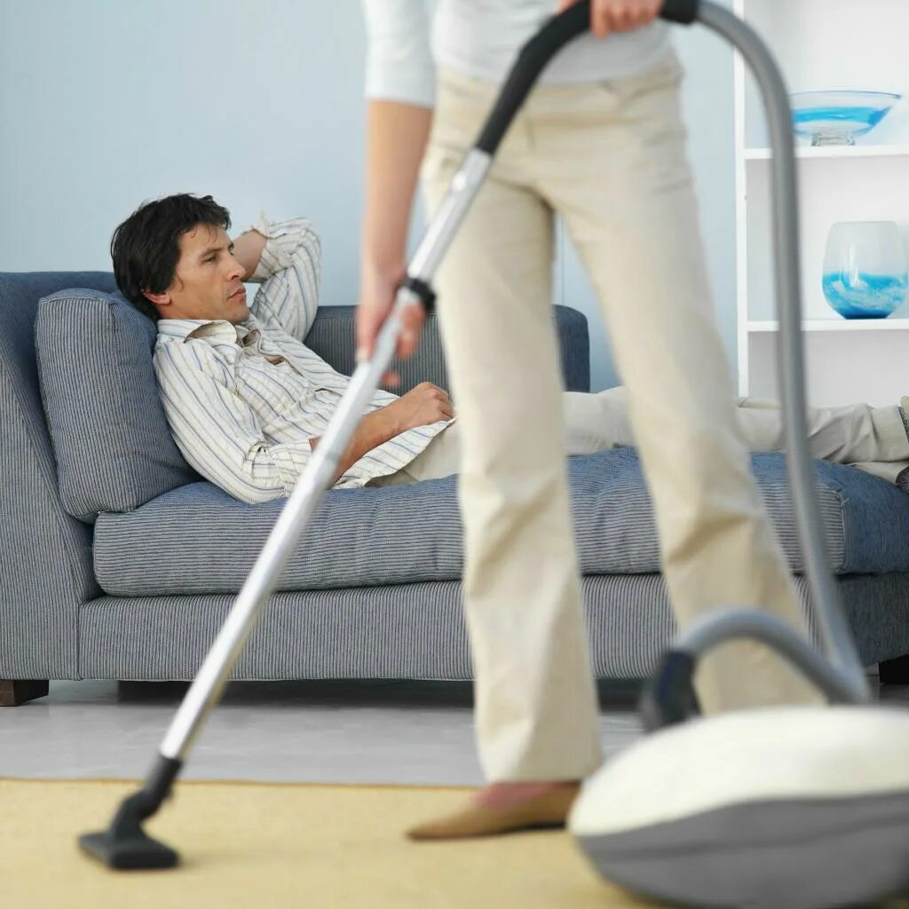 снять чужую работу. босс и подчиненные. снять чужую работу. женщина пылесосит мужчина на диване. женщина в гневе.