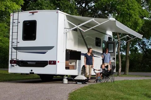 Family sitting under the awning of their Winnebago Intent. 