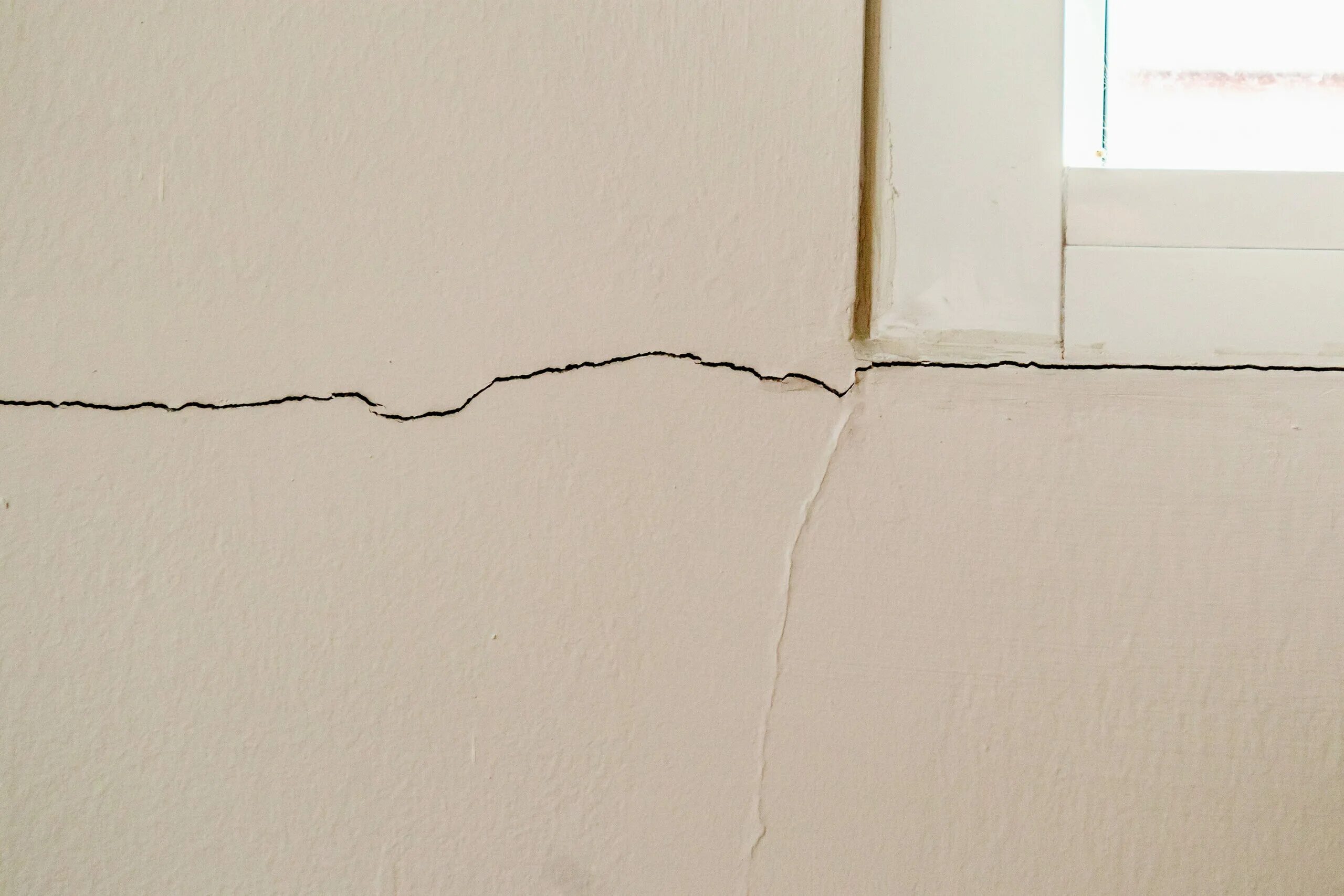Трещины вокруг. Трещина в доме. Много трещин на стене. Трещины возле окон.