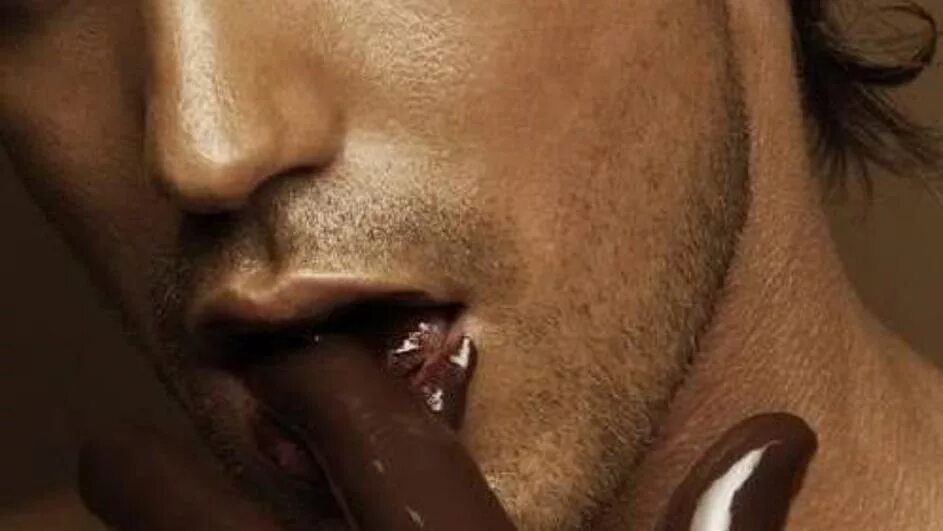 Мужчина облизывает губы. Облизывает шоколад. Губы мужские.