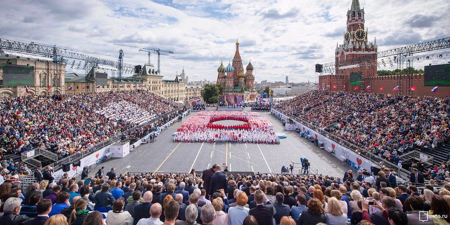 На сцене установленной прямо на площади играют. Красная площадь праздник. Москва люди.