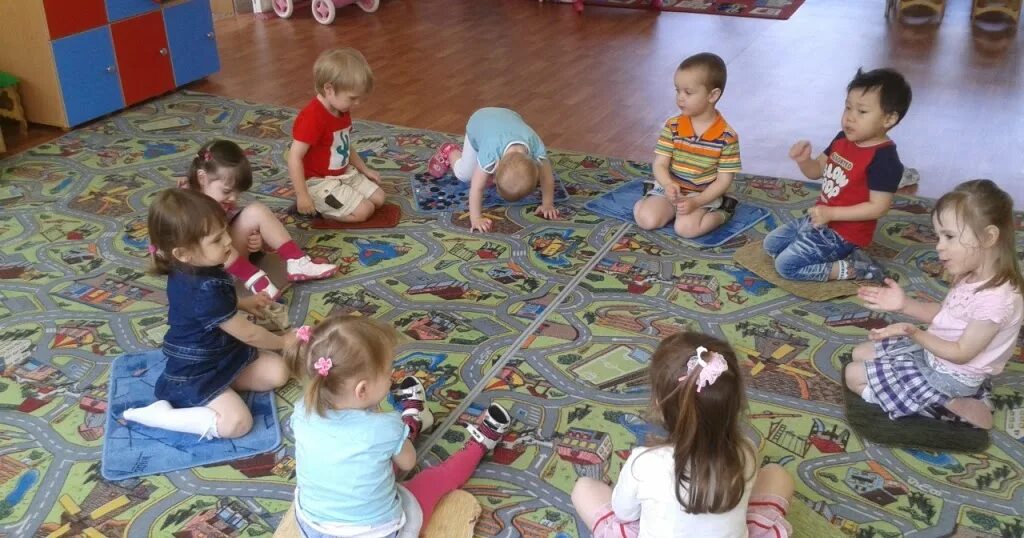 Игры в кругу в детском саду. Дети сидят в саду. Ребенок сидит на ковре. Дети в кругу в детском саду. Дети в кругу в ДОУ.
