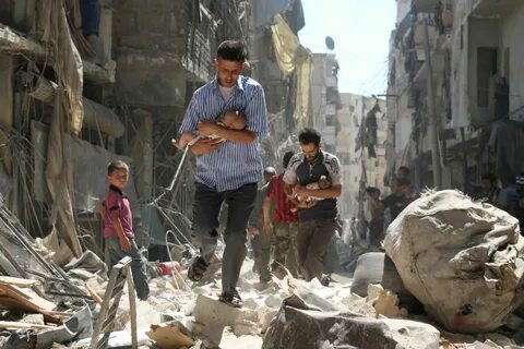 Сирийские мужчины несут детей через завалы зданий