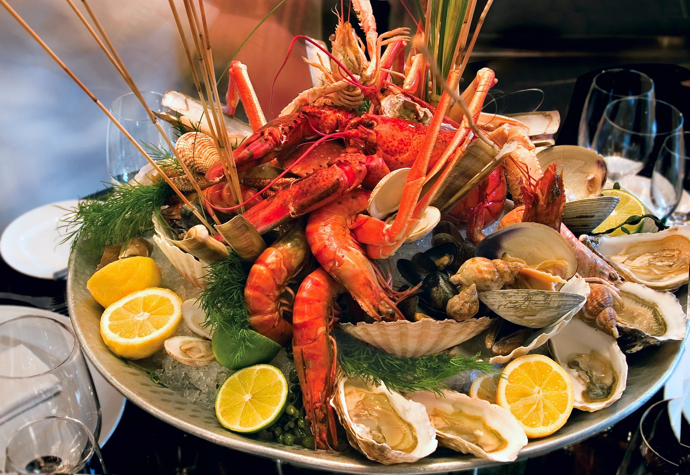 Морской ужин. Устрицы, лангусты, омары. Стол с морепродуктами. Кафе морепродуктов. Тарелка с морепродуктами.