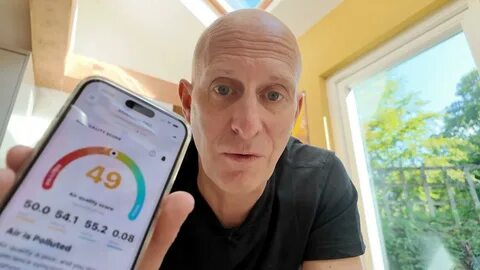 A man holds up a mobile phone showing declining air quality within his home...
