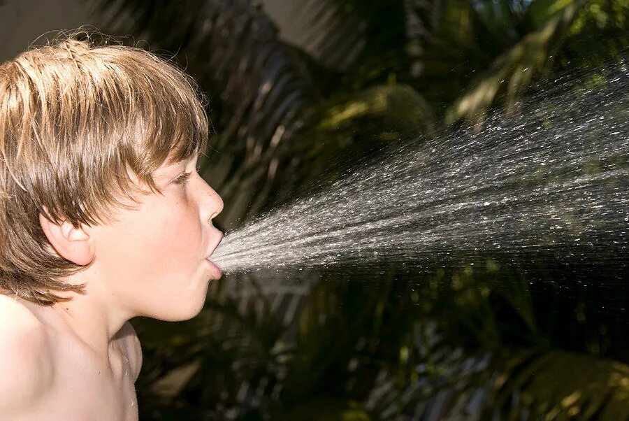 Мальчик плюется. Мальчик брызгает водой. Плюется водой. Струя воды в лицо.