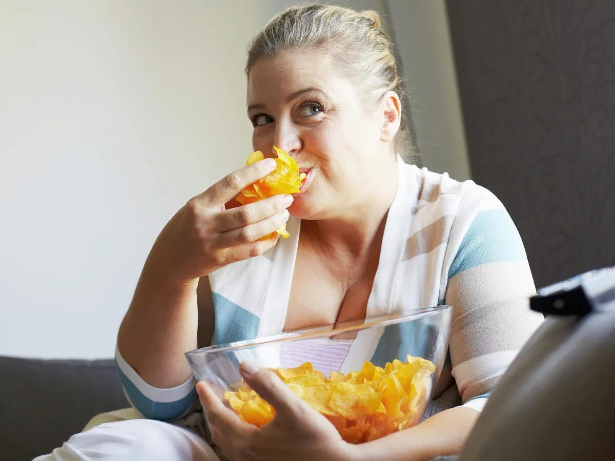 Жирный человек с чипсами. Девушка ест чипсы. Чипсы с женщиной. Толстый человек ест чипсы.