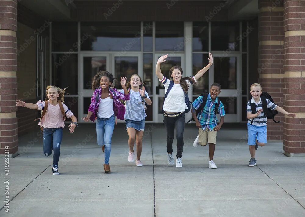 Group of elementary school kids running in a school corridor фотография Stock Ad