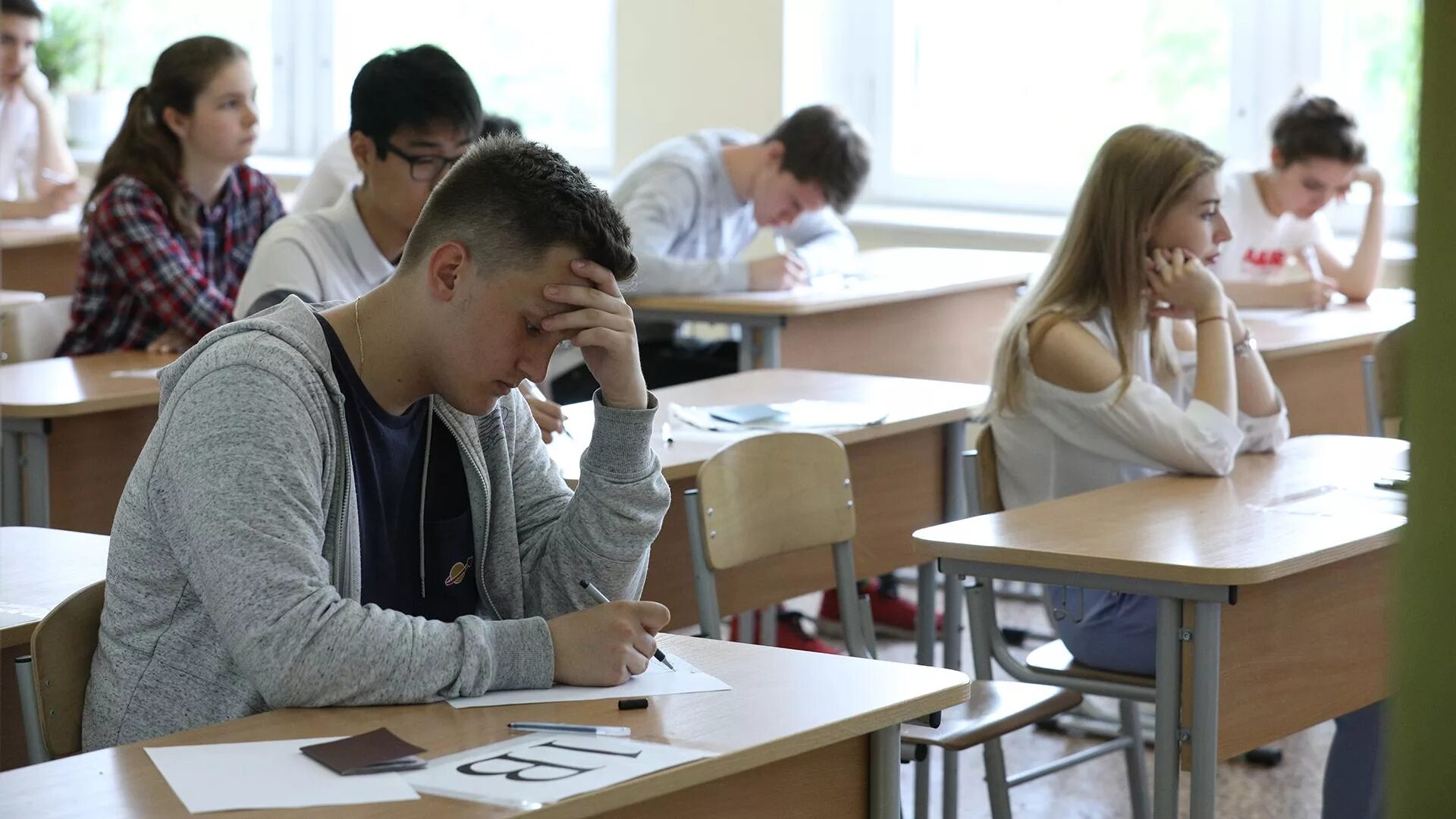 Будут ли экзамены в школе. Старшеклассники за партой. Ученик на экзамене. Подросток на экзамене. Выпускной экзамен в школе.