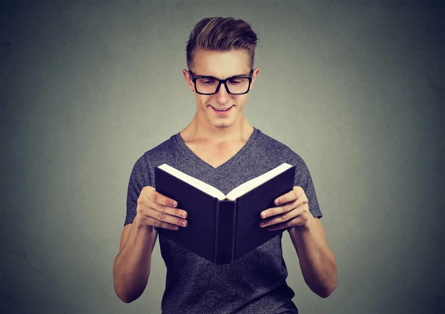 Он смотрит в книгу. Парень в очках читает книгу. парень с книгой на сером фоне. человек в очках читает на стене. читает книгу с умным взглядом прикол.