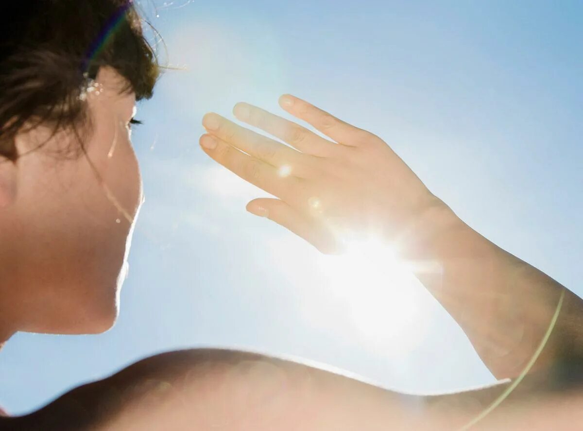 Воздействие УФ лучей на кожу. Прикрывает лицо рукой от солнца. Солнечные лучи на коже. Воздействие солнечных лучей.