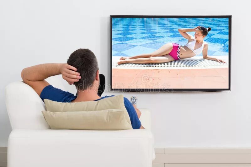 He is watching tv at the moment. Человек перед телевизором. Диван и телевизор человек. Человек сидит перед телевизором. Мужчина перед телевизором.