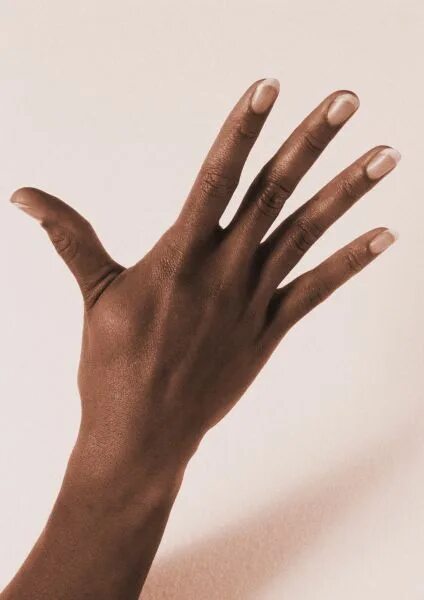 жест мир пальцами. указательный палец. ладонь на темном фоне. тонкие пальцы. маникюр одна рука черная.