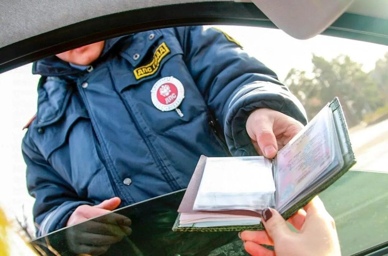 Наказание за управление автомобилем. Сотрудник ДПС проверяет документы. Полиция выписывает штраф.