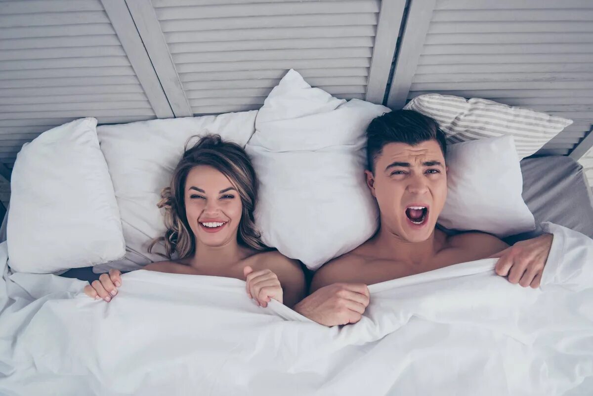 удивила в кровати. удивила в кровати. удивленная девушка в постели. удивила в кровати. смеется над мужчиной.