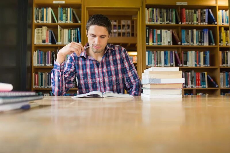 Мужчина за библиотечным столом. Мужчина учится. Два человека сидят в библиотеке. Человек в архиве.