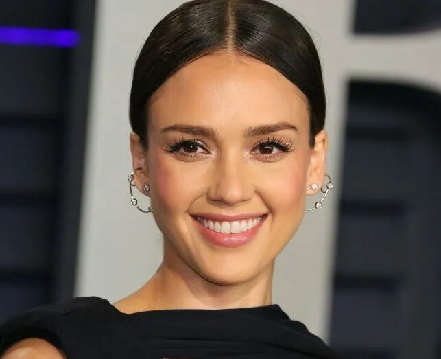 Jessica Alba looks cute in a Letterman jacket and bow in her hair as she takes a