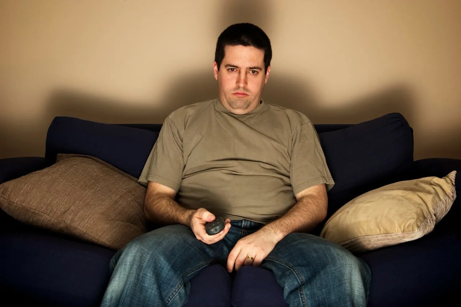 Телефоны одиноких мужчин. Человек сидит на диване. Малоподвижный образ жизни. Скучный мужчина. Сидячий образ жизни.
