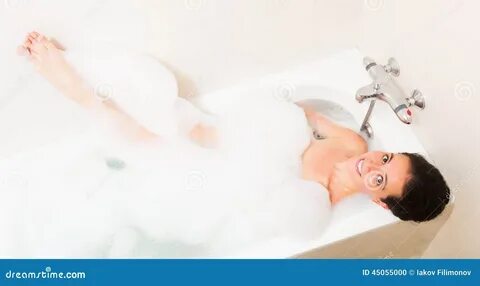 Beautiful girl laying with foam in bathtub.