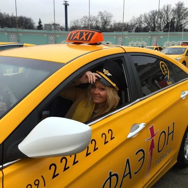 За рулем такси. Желтая машина такси. Девушка в такси. Девушка таксистка.