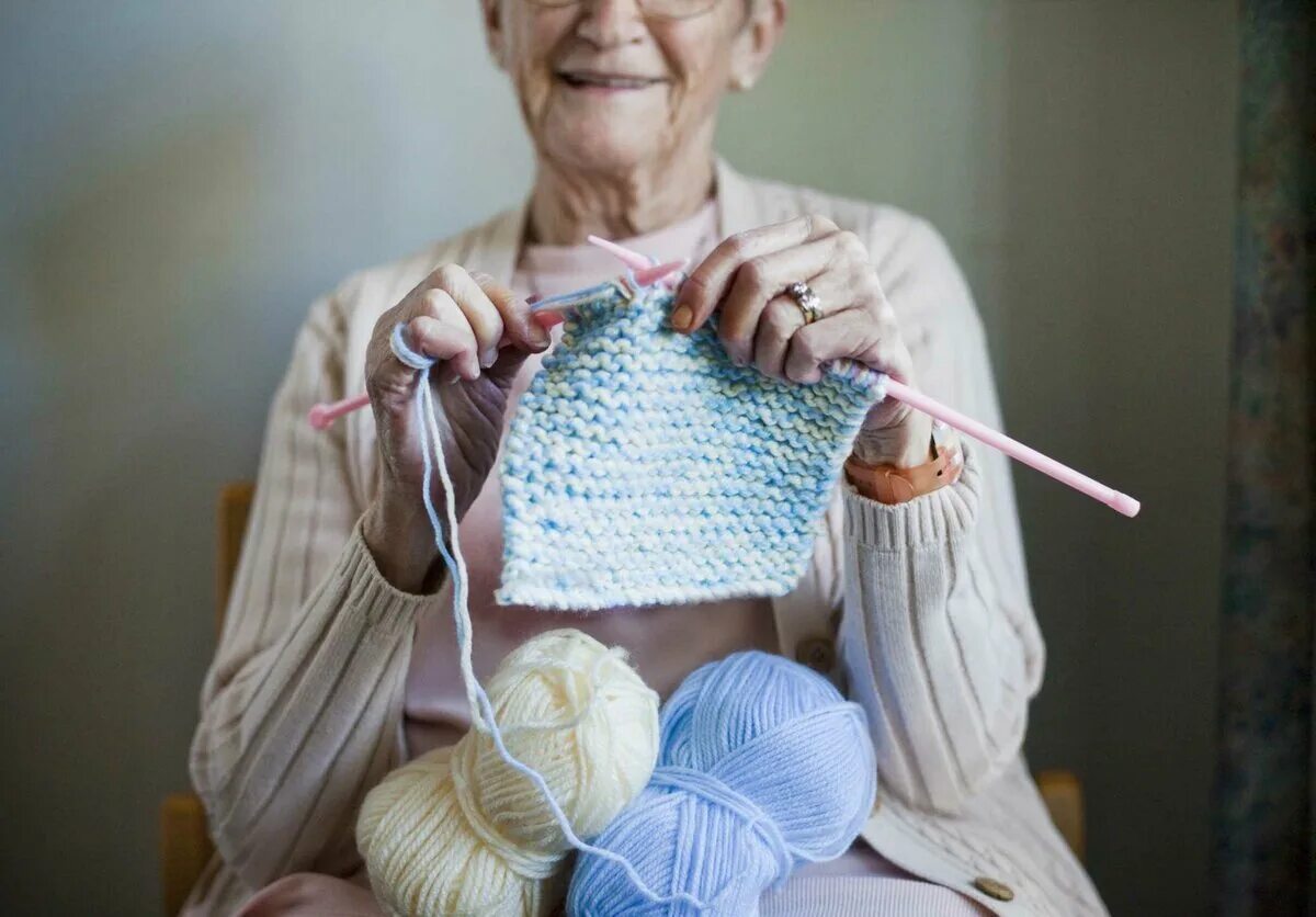 Бабушка снизу. Книттинг. Хобби вязание. Спицы и пряжа. Вязальные спицы в руках.