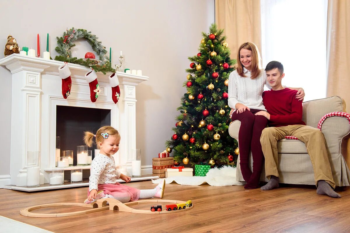 украшение елки семьей. семья наряжает елку. семья новый год фотосток. фотосессия у новогодней елки всей семьей. новый год наряжаем елку.