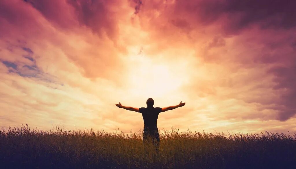 Хвала богу земли. Парень с распростертыми руками. Поклонение христианское. Мужчина в лучах солнца. Слава в вышних богу и на земли мир.