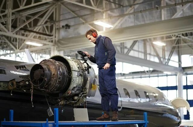 Aircraft Mechanic Repairs an Aircraft Engine in an Airport Hangar Stock Image - 