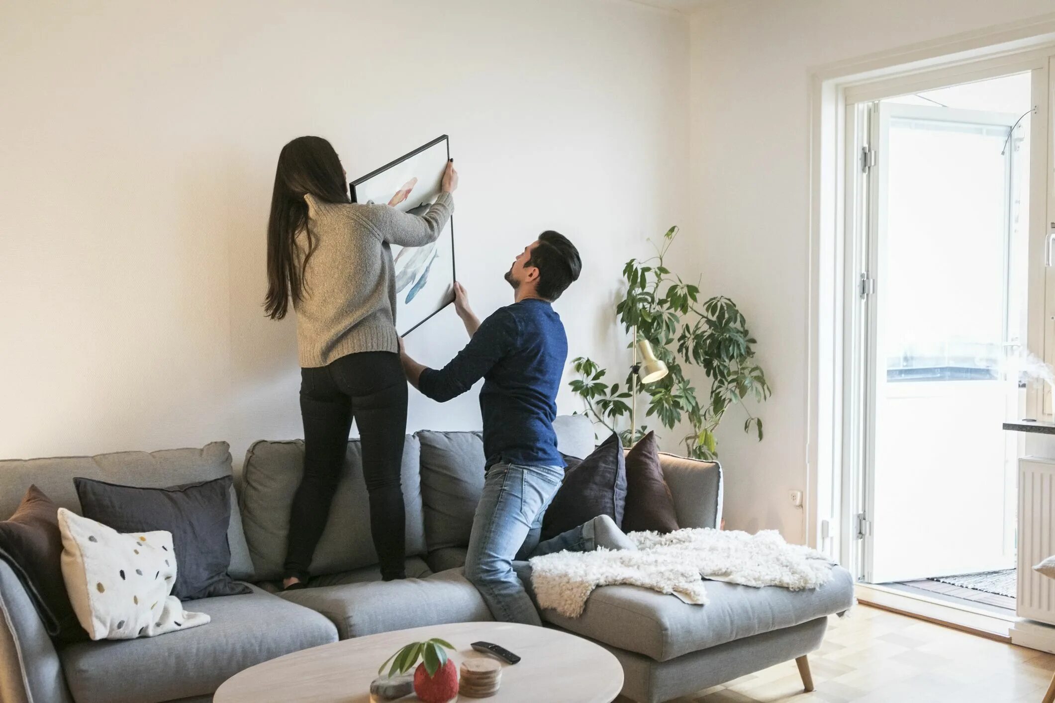Повесить девушек. На что вешать картины на стену. Женщина вешает картину на стену. Пара выбирает квартиру. Девушка в зале.