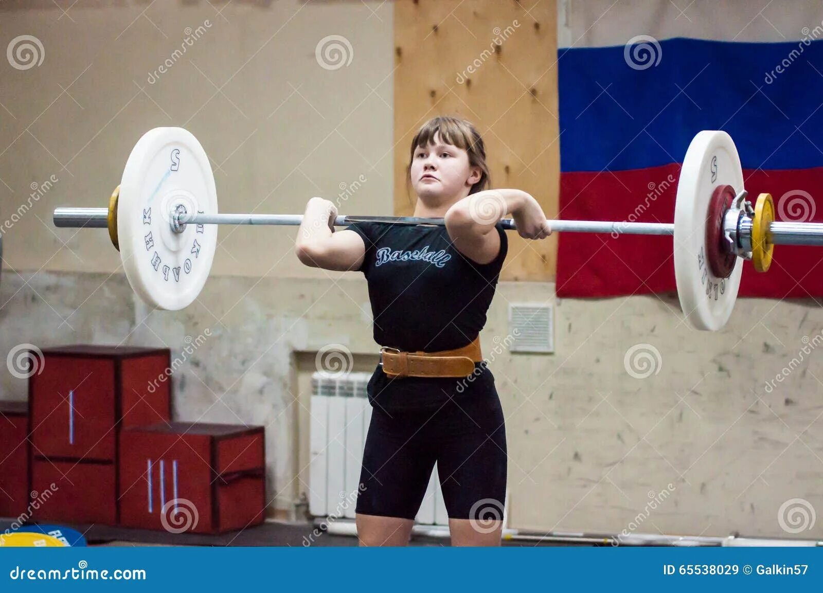 Девушка поднимает штангу
