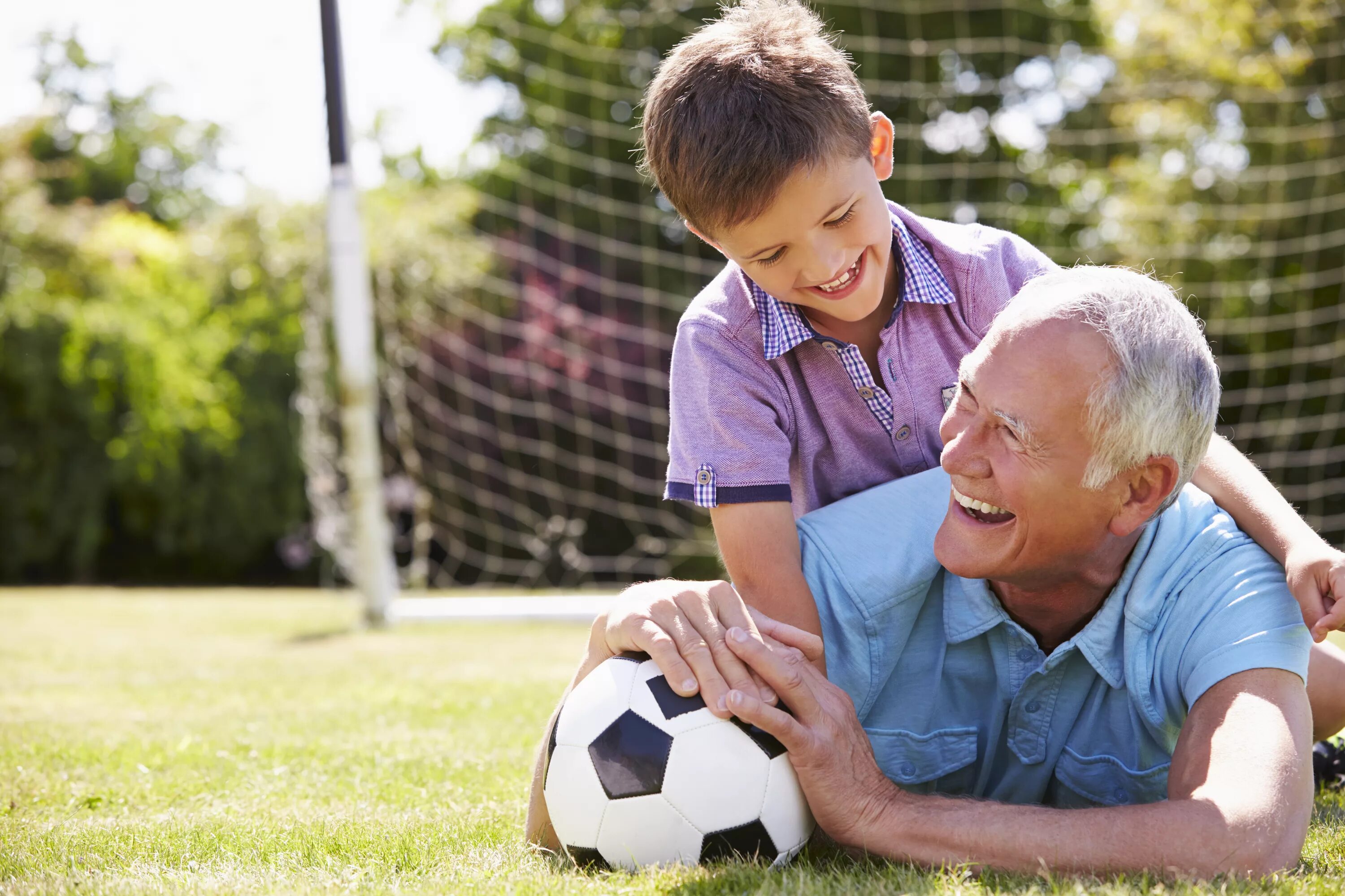 Дедушка играет футбол. Дедушка и внук. Дедушка внук футбол. Дети и пожилые занимаются спортом. Дедушка играет с детьми в футбол.