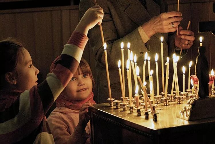 Подсвечник в храме. Церковь. Человек молится в храме. Как людям ставят свечи. Горящие свечи в храме.