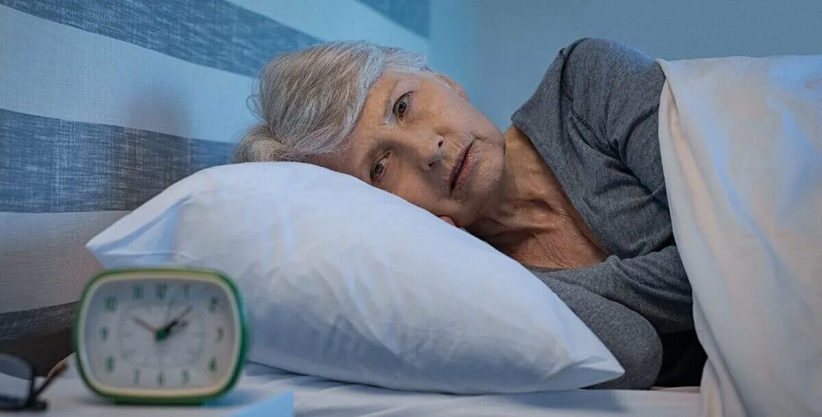 Плохой сон. Нарушение сна. Тревожный сон в постели. Пожилой человек спит. Бессонница в пожилом возрасте.