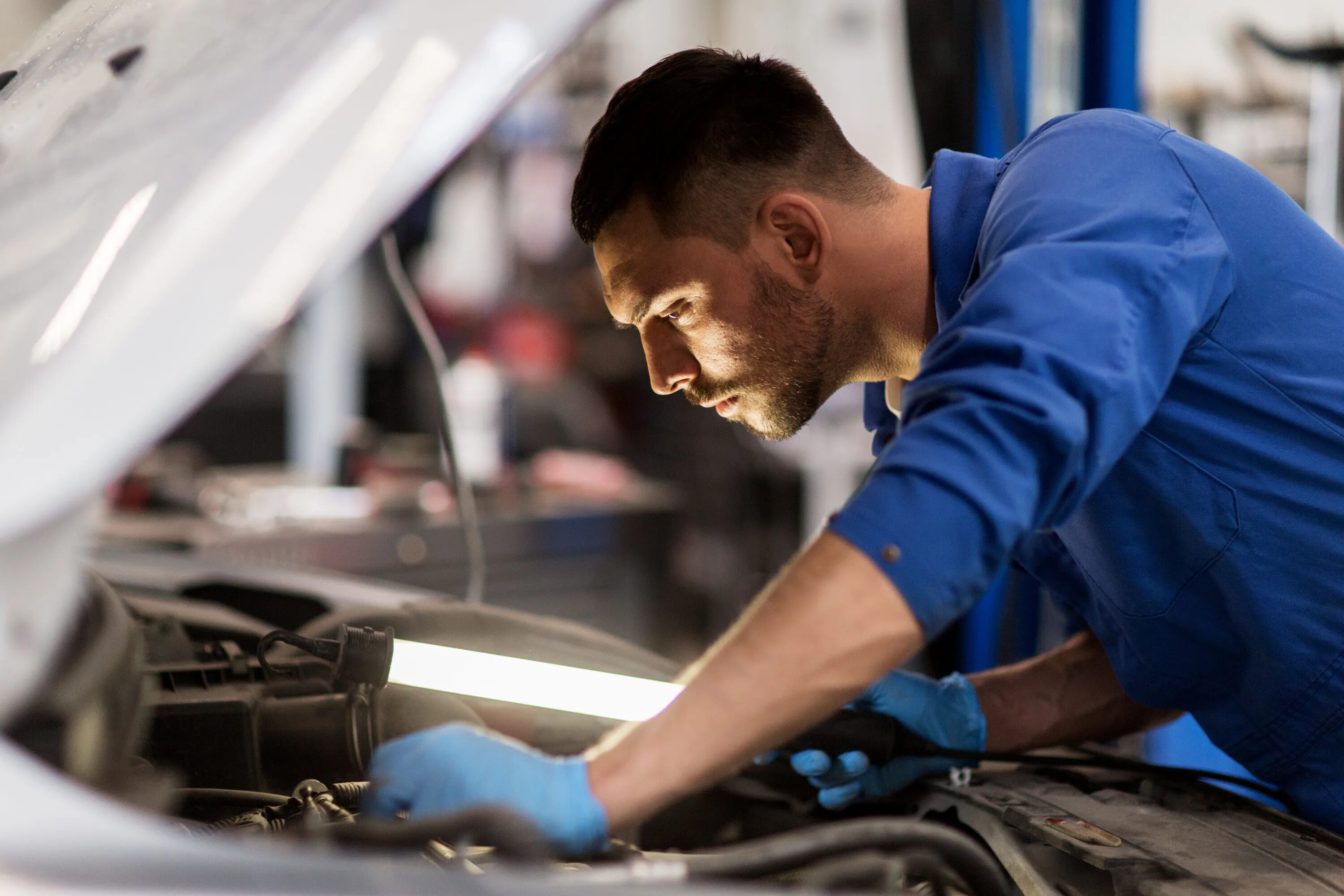 выживания автомеханики. фото механика в жизни человека. автомастерская. мужчина в гараже. человек ремонтирует машину.