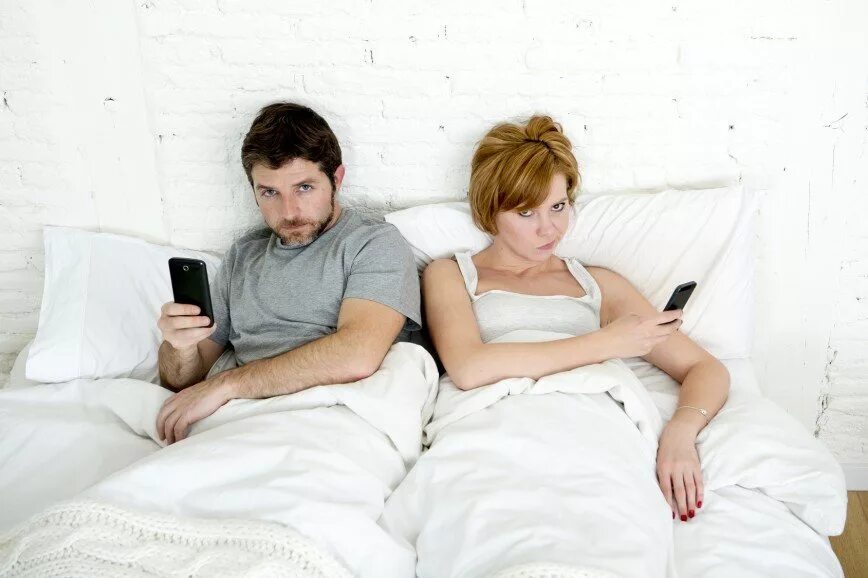 Супруги в телефонах. Муж и жена в телефонах. Муж и жена гаджеты. Двое с телефонами в кровати.