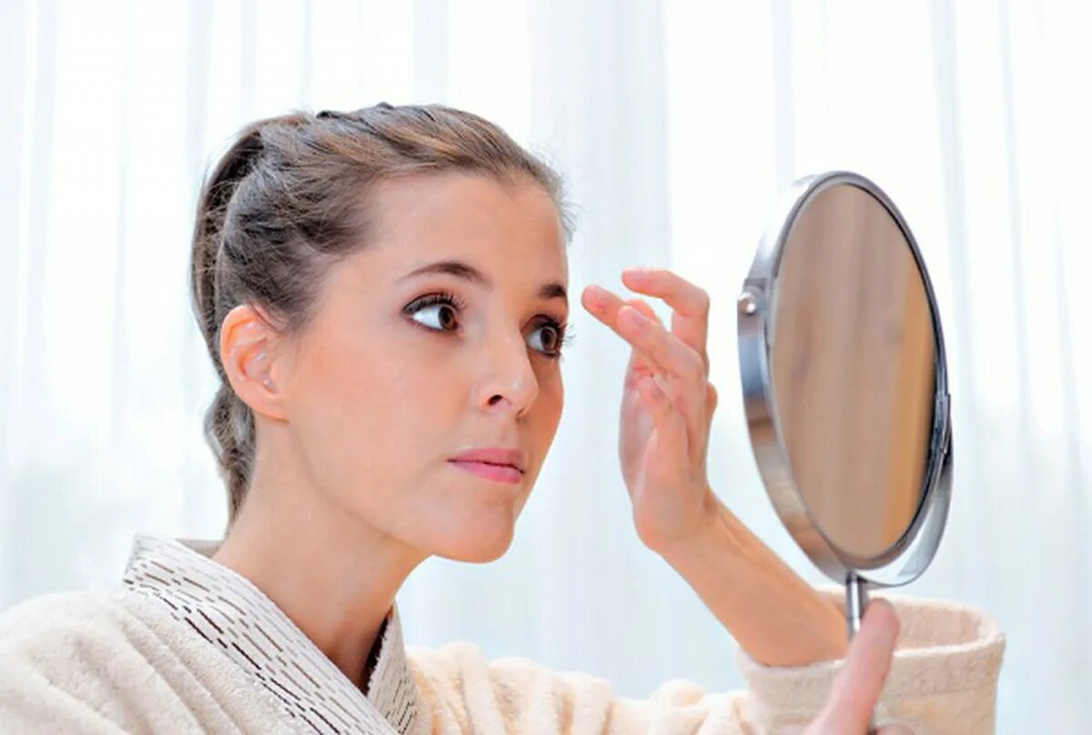 Зеркало для макияжа. Мейкап зеркало. Злоупотребление косметикой. Девушка поправляет косметику в зеркало.