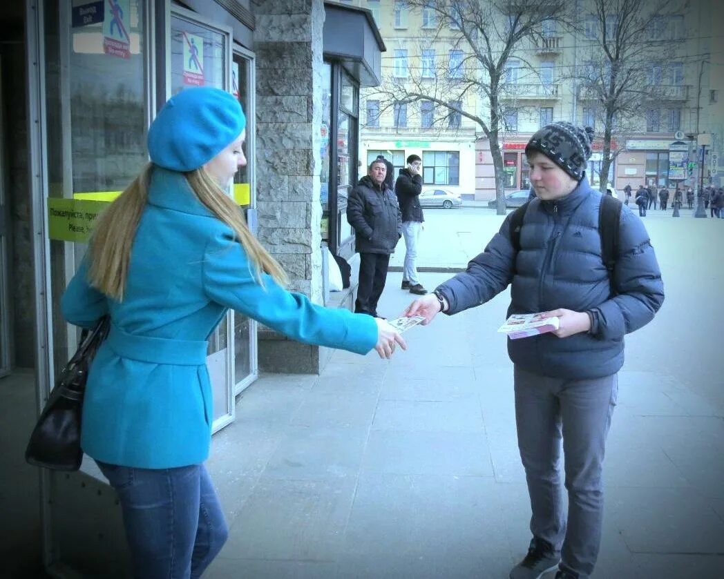 Раздает листовки. Парень раздает листовки. Раздают листовки на улице. Раздача листовок на улице. В школах детям раздают