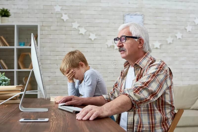 Старик сбоку за столом с семьей. Grandfather with Computer. Чем пользуются старики. Boy helping Grandad with Computer. Boy old man