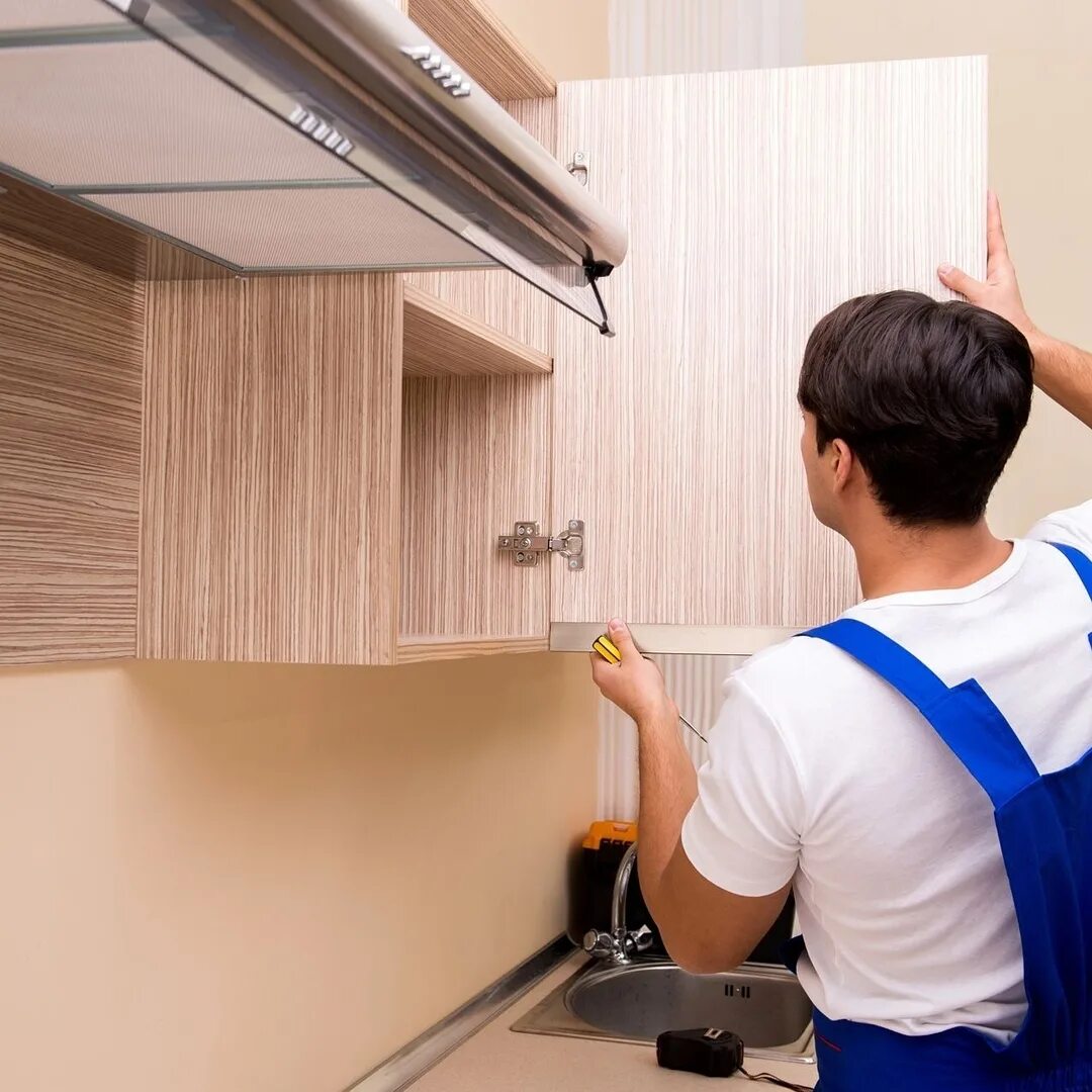 евроремонт. монтаж кухни. монтаж кухонных шкафов. сборка кухни. рабочий собирает кухню.