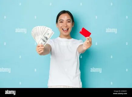 Excited happy asian girl showing cash of dollars and rejoicing, earn fist p...